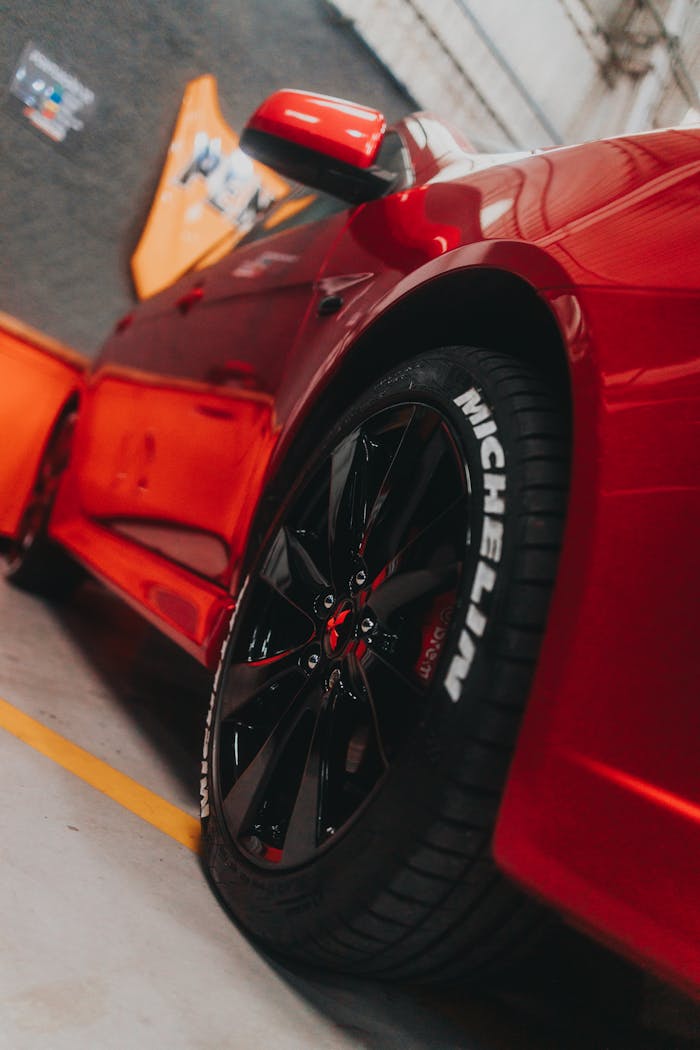 Close-up of a sleek red sports car showcasing a Michelin tire in a garage setting.
